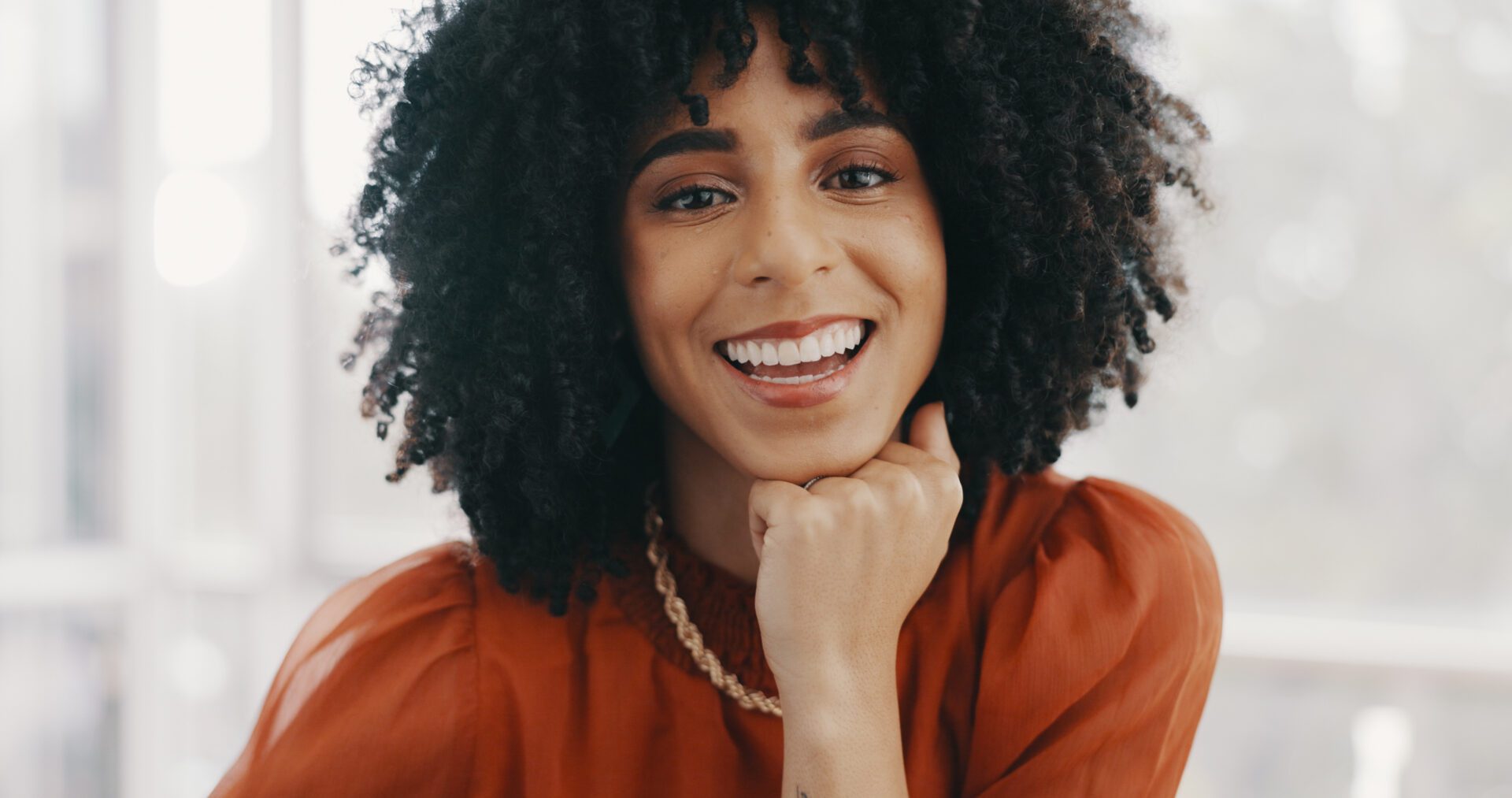 Face, vision and mindset with a business black woman sitting at a desk with her hand on her chin. Portrait, happy and smile with a female employee thinking about future growth or company development.