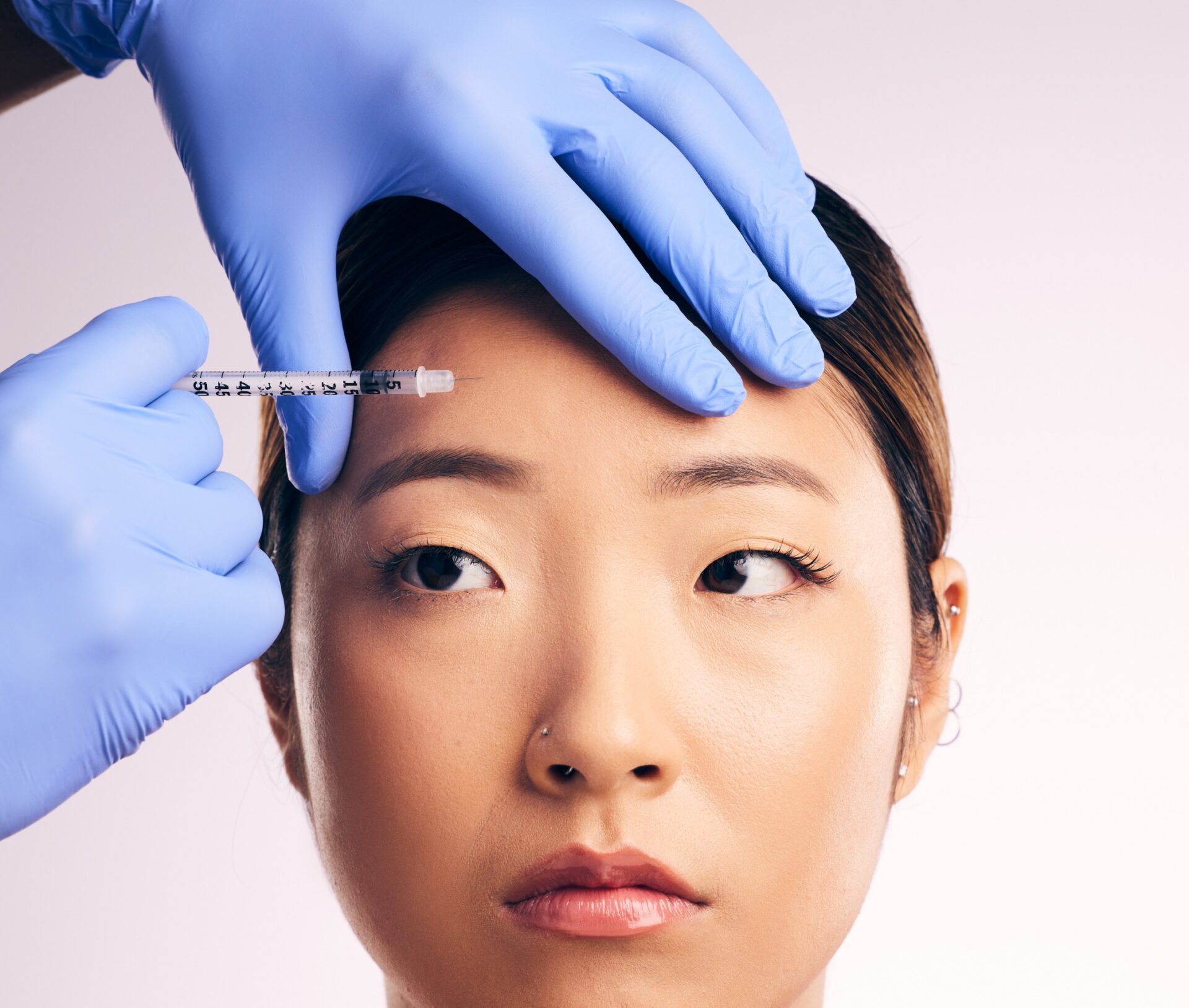 A woman getting her eyebrows examined by a doctor