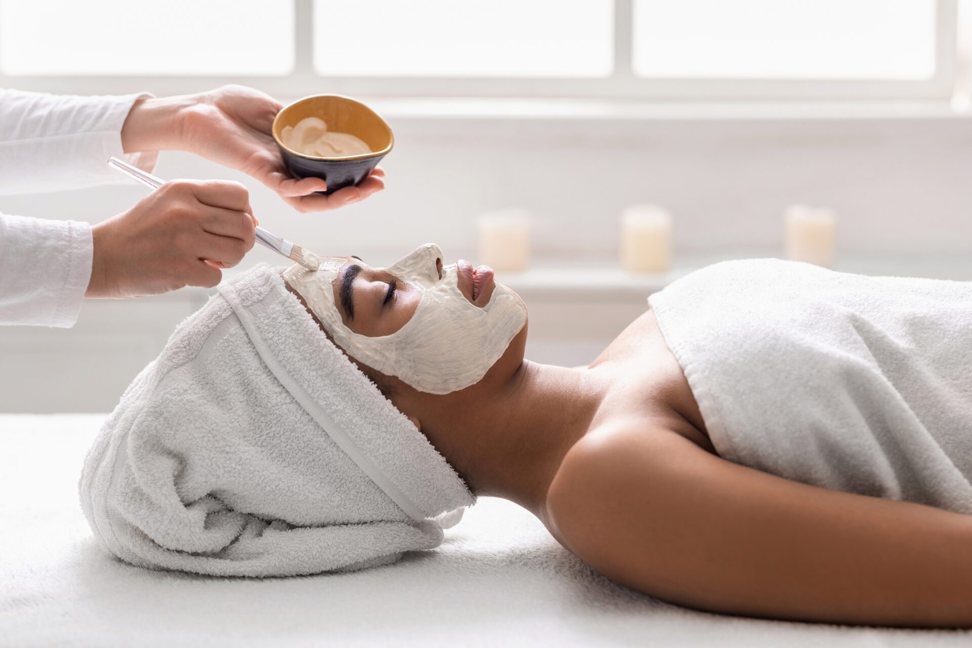 African girl getting face cleansing procedures at spa