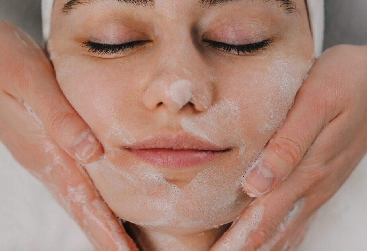 Cosmetologist's hands cleansing the skin with foam